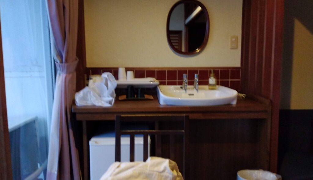 湯快リゾート越乃湯で宿泊した部屋にある手洗いと冷蔵庫と鏡の画像